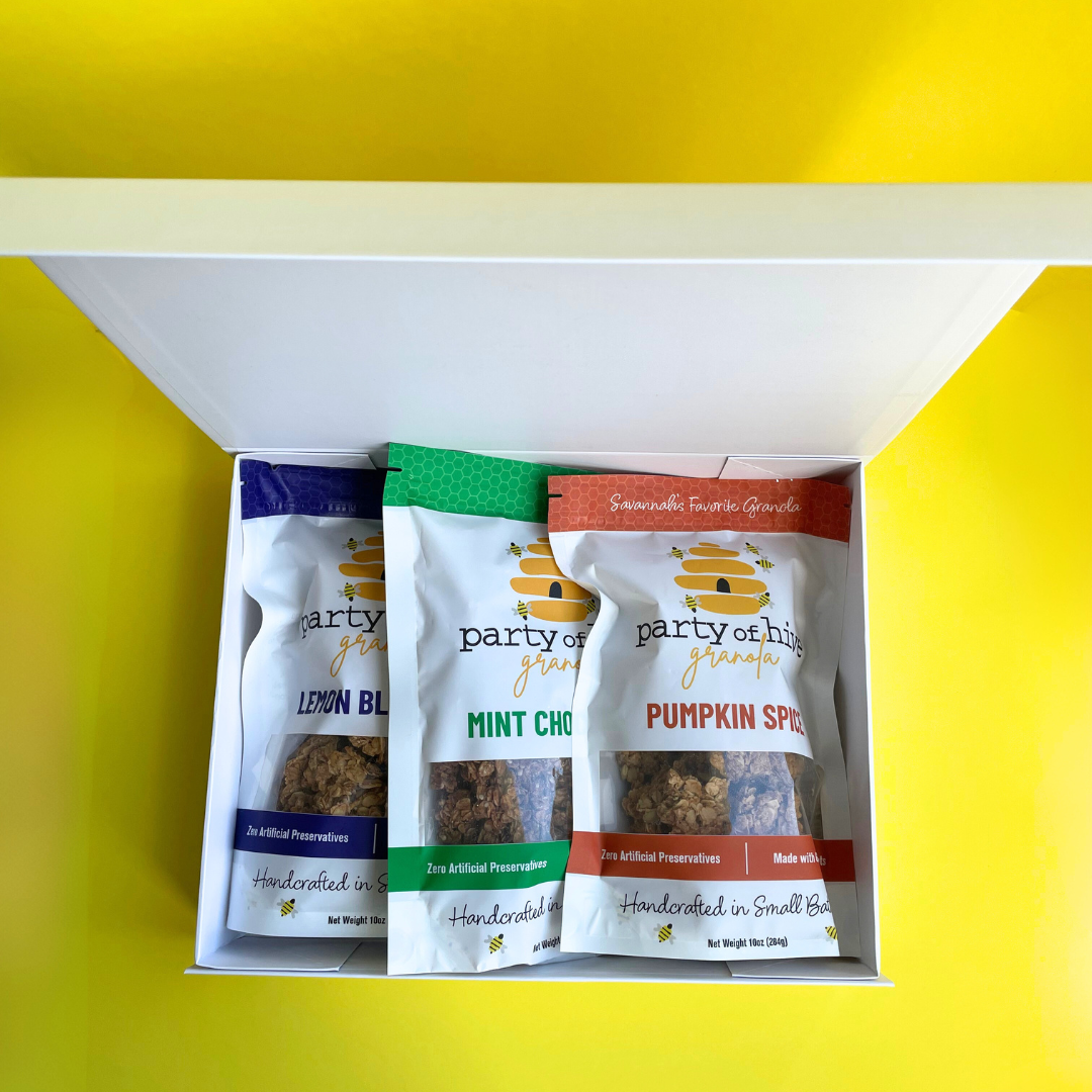 Assorted granola packages from 'party of hive' in a box on a yellow background