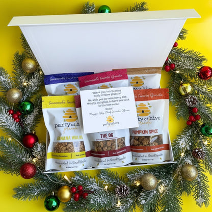 Assorted snack packages in a decorative box with Christmas decorations on a yellow background