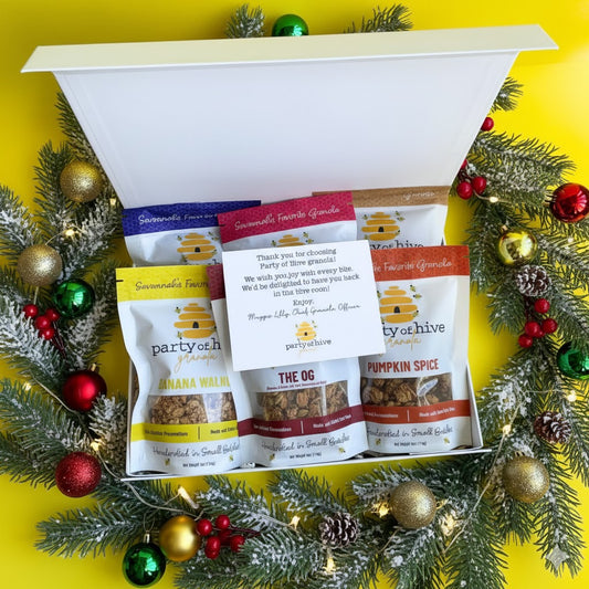 Assorted snack packages in a decorative box with Christmas decorations on a yellow background
