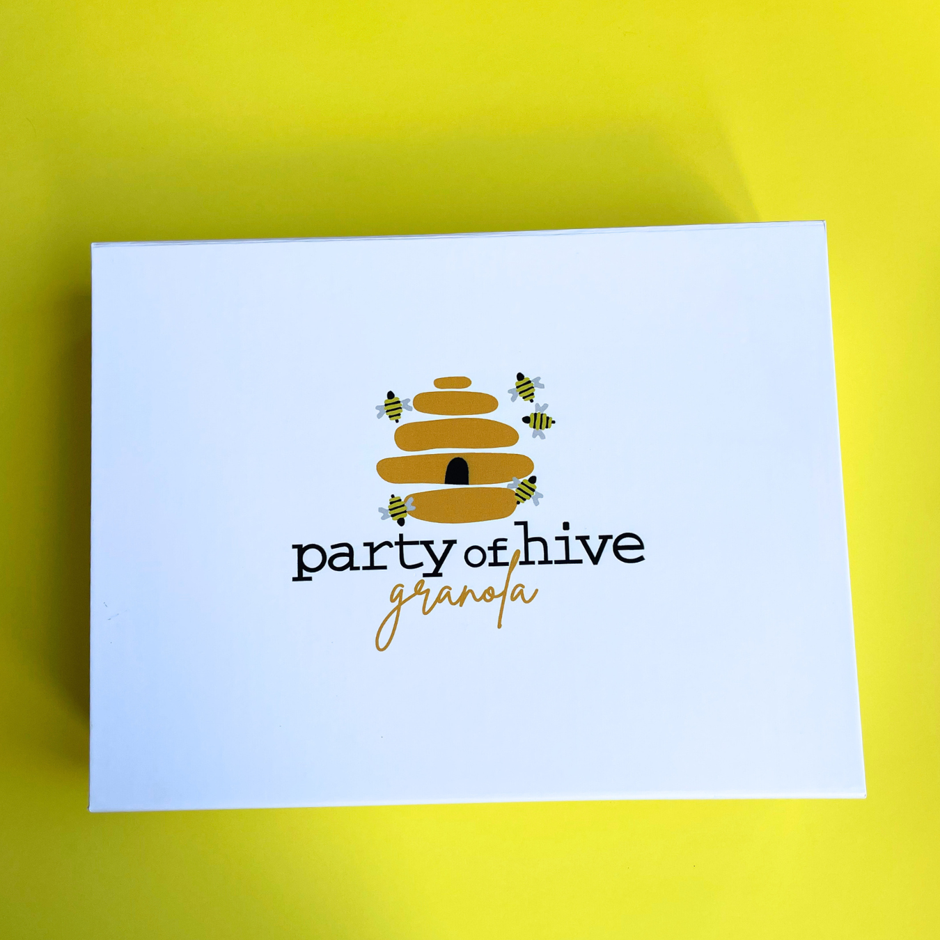 White gift box with 'party of hive granola' design on a yellow background